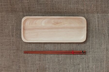 Top view : wood chopsticks and wood tray on canvas texture background.の写真素材