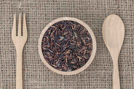 Top view : Brown rice (Rice Berry) in wooden bowl on sack texture.の写真素材