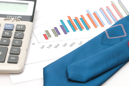 Business concept : Calculator and necktie on graph background.の写真素材