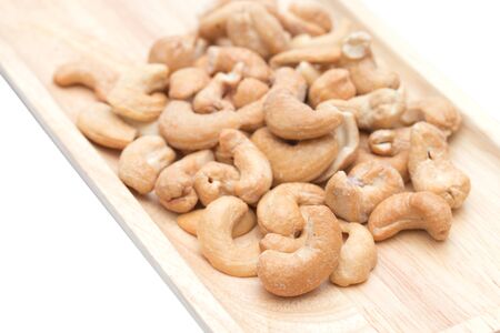 Cashew nuts in the wooden tray isolated on white background.の写真素材