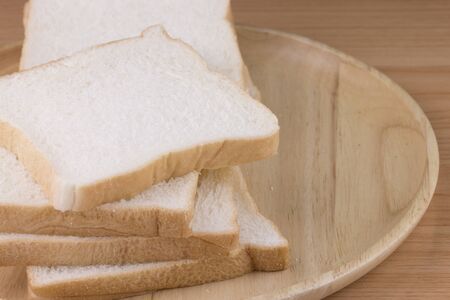 Whole wheat bread on wooden plate placed of wooden background.