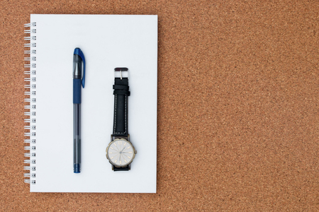Pen and watch place on note book on a wooden background. Concept of creative office. Top view.の写真素材