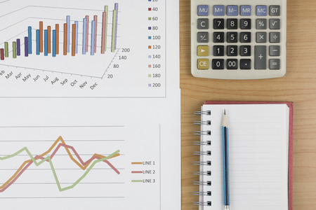 Business concept : Pencil placed on notebook with  calculator and graph on wood table