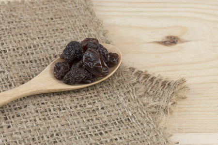 raisins in spoon on wooden table.の写真素材