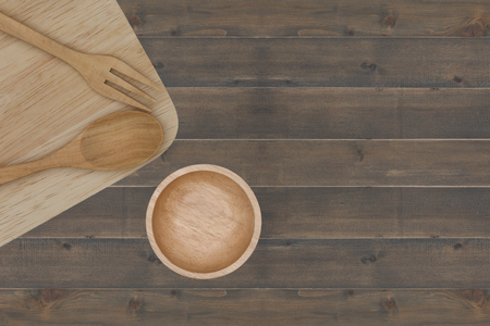 kitchenware : spoon, fork, cup, chopsticks and cutting board placed on wooden tableの写真素材
