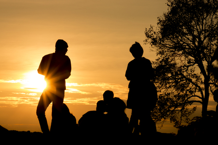 silhouette of people relax at the cliff and mountains with sunset in the eveningの写真素材