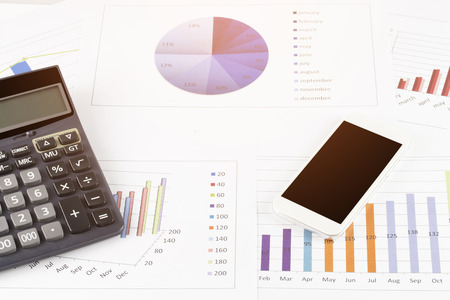business concept : graph with smartphone and calculator on stock market report as backgroundの写真素材
