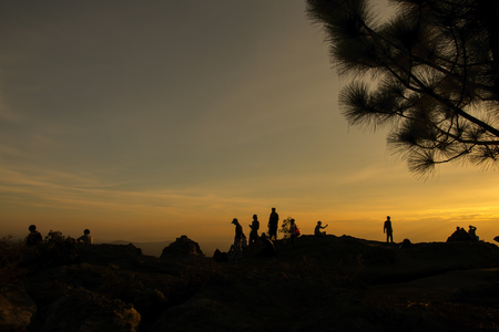 silhouette of people relax at the cliff and mountains with sunset in the evening の写真素材