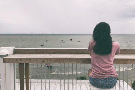 Woman sitting on chair and looking at the seaの写真素材
