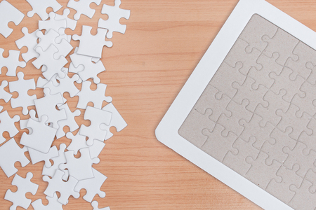 White jigsaw puzzle on wood table.の写真素材
