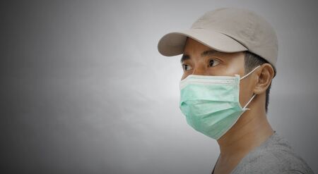 Close up of young male wearing protective face mask on dark background.の写真素材