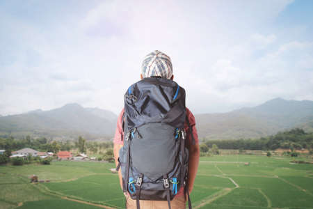 Young man with backpack looking at rice field and village in countryside.の写真素材