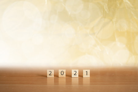 new year 2021 with wood cube on gold background.