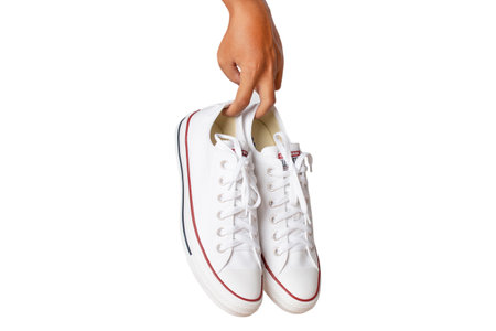 Bangkok, Thailand, August 30, 2020: Hand holding white Converse all star sneakers isolated on white background.のeditorial素材