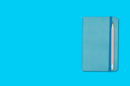 Note book and pencil isolated on blue background.の写真素材