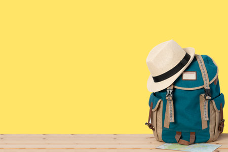 Backpack with hat and map isolated on yellow background.の写真素材