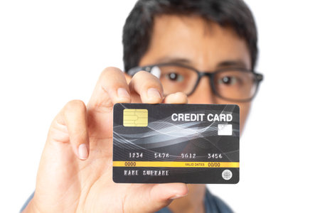 Young man showing credit card and reach it out to the front isolated on white background.の写真素材
