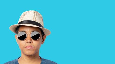 Young man wearing sunglasses and straw hat isolated on a blue background. clipping path.