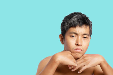 Portrait of a thoughtful young man something, a man takes off his shirt. isolated on blue background. clipping path.の写真素材
