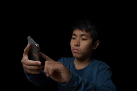 Young man using smartphone on black background.の写真素材