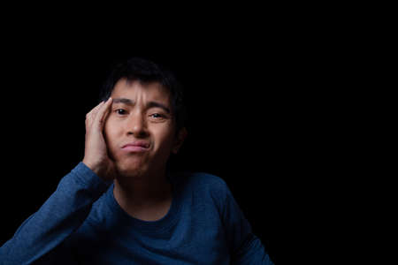 Asian man getting bore something on black background.の写真素材