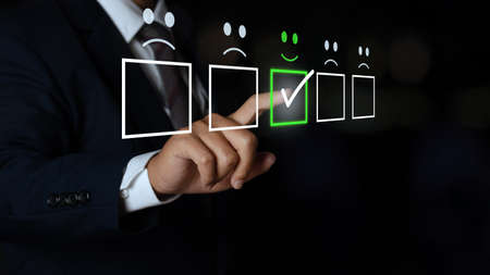 business man touching the virtual screen on the smiley face icon on the digital touch screen....
