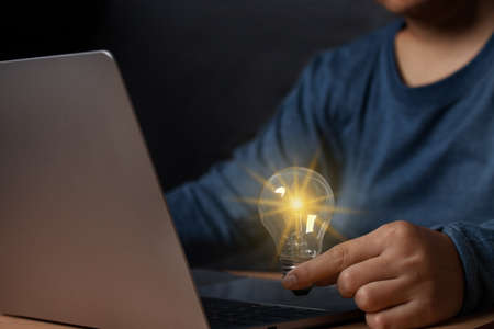 Businessman holding light bulb and using a laptop. Idea of â€‹â€‹inspiration.