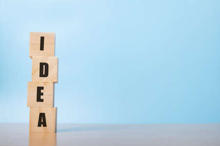 arranging wood cube stacking with idea text on blue background with free text space.
