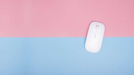 wireless mouse for computer and laptop on blue and pink background. top view. copy space.