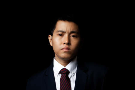 Portrait of asia businessman in suit isolated on black background.の写真素材