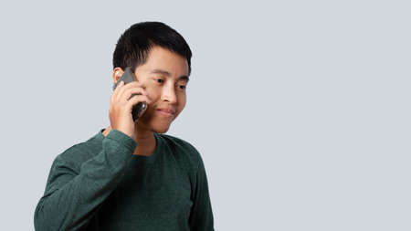 Portrait of Asia man talking smartphone isolated on gray background.の写真素材