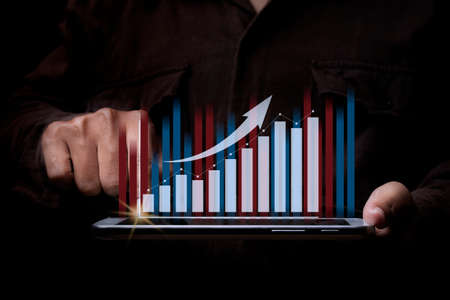 Businessman with a tablet in hand and touching on the screen That shows a financial chart. concept of business strategy and business finance. Digital marketing.の写真素材