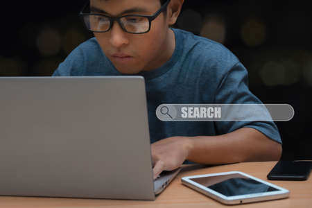 Young man with eye glasses browsing at his computer laptop to searching information.の写真素材
