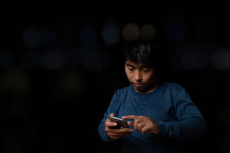 Young man using smartphone on black background.の写真素材