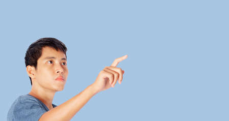 Young man pointing finger touching on screen isolated on blue background.の写真素材