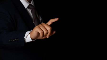 Young businessman pointing finger touching on screen black background. copy space.の写真素材
