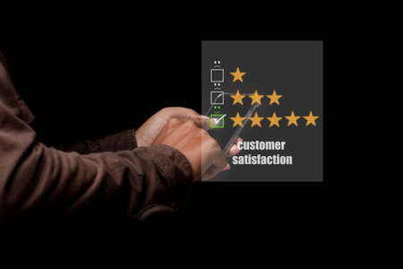 Young man using smartphone with virtual screen on the smiley face icon on the digital touch screen. Customer service evaluation concept.の写真素材