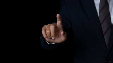 Young businessman pointing finger touching on screen black background. copy space.の写真素材