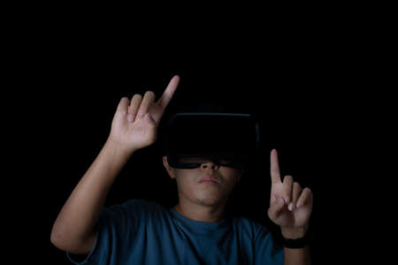 Studio portrait man wearing VR Headset touching something by his fingers on black background....