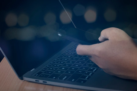Man using smartphone and computer laptop surfing the internet on office table, online, working, business and technology, internet network communication on bokeh light background.の写真素材