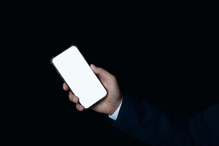 Businessman hand holding smartphone with blank white full screen on black background.の写真素材
