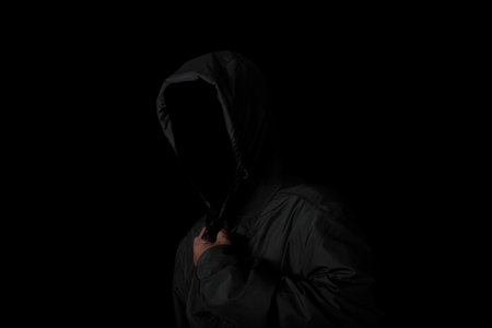 Scary and creepy man hiding in the shadows, with the face and identity hidden with the hood, Dark...