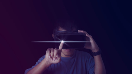 Close up of young man touching digital screen with finger on dark background. Innovation technology...