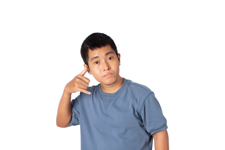 Portrait of young single man wearing t-shirt making call me gesture, sign with hand shaped like phone isolated on white background. Positive human emotions, face expressions.の写真素材
