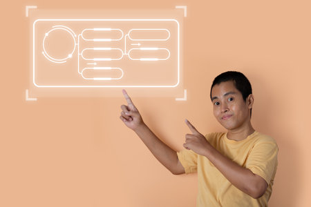 Young man pointing his finger with blank text box isolated on orange studio background. copy space.の写真素材