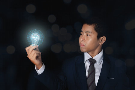 Businessman holding glowing light bulb with symbol brain and creative thinking ideas. innovation concept.の写真素材