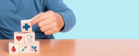 Hand chooses a emoticon icons healthcare medical symbol on wooden block, Insurance for your health concept. copy space.の写真素材