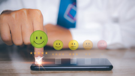 Man using smart phone choosing happy smile face positive mindset selection for feedback review satisfaction service. rating very impressed. Best quality. Customer satisfaction experience concept.の写真素材