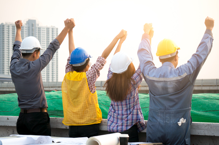 Engineers wearing safety helmet raising hand feeling successの写真素材