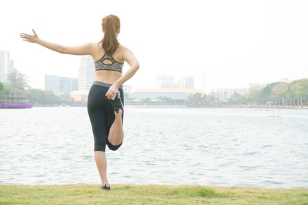 Asian sport woman feeling relax with yoga on lake in parkの写真素材